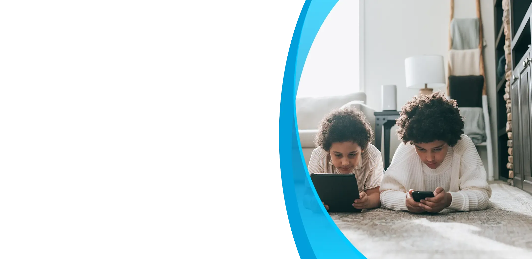 Two children lie on a living room floor, each focused on a tablet and smartphone.